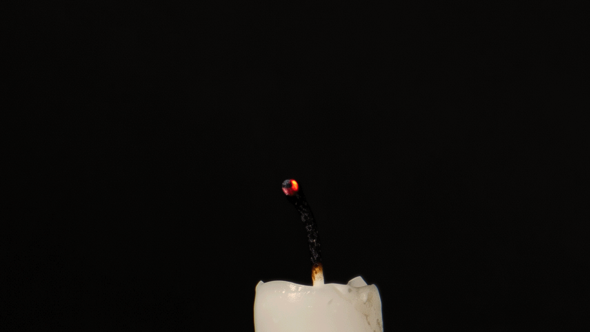 Animated candle flame glowing in a dark, atmospheric setting with warm amber light and soft cinematic shadows, creating a cozy and luxurious mood for the Silk and Ember launch collection